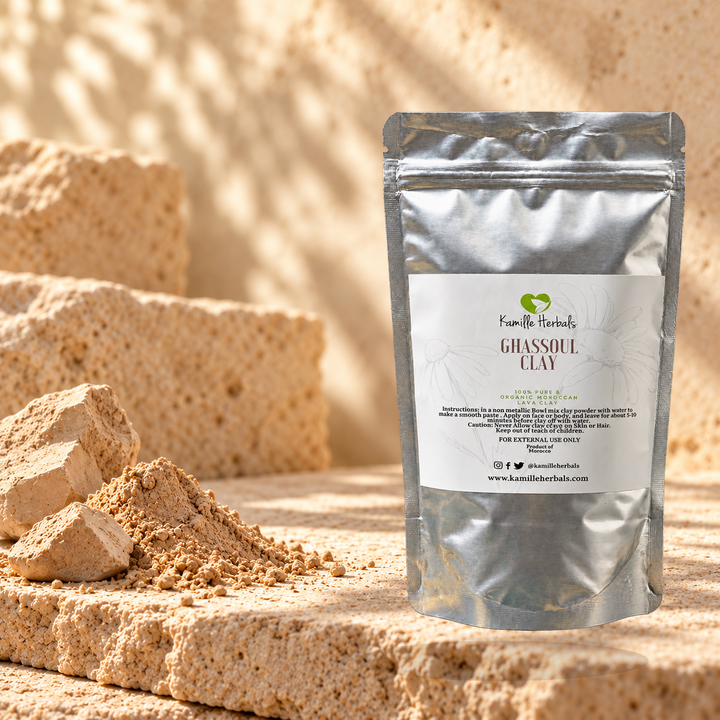 Ghassoul Clay 100g pouch with Moroccan clay powder and raw clay pieces on warm limestone